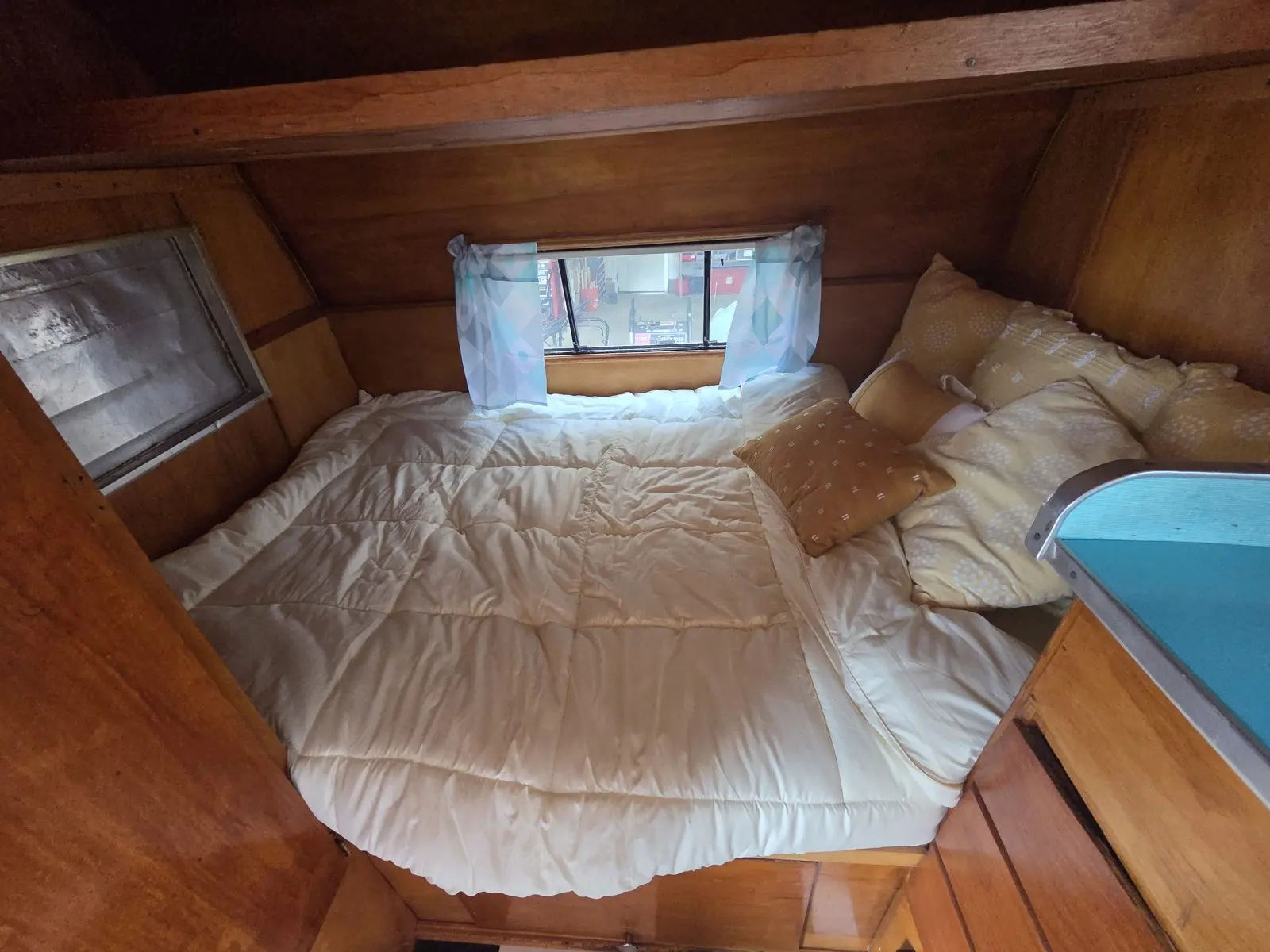 Rear bed beneath curtained windows.