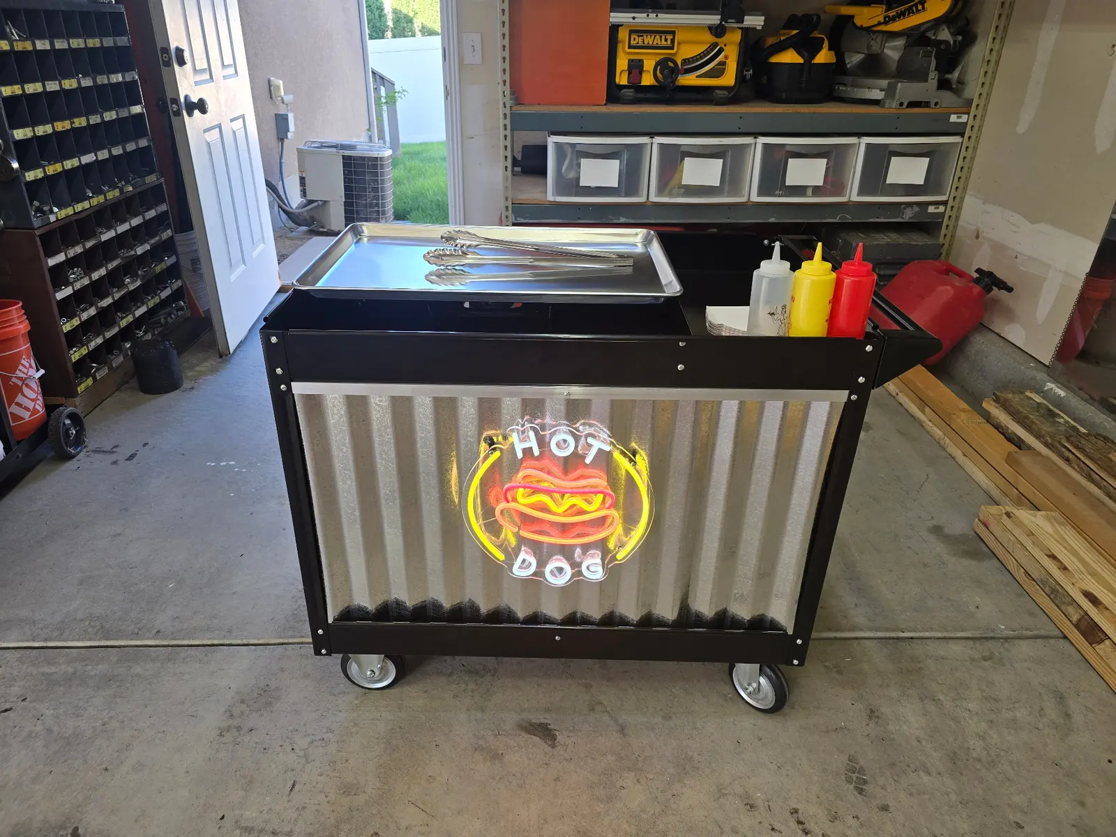 Black hot dog cart with circular neon HOT DOG sign in garage