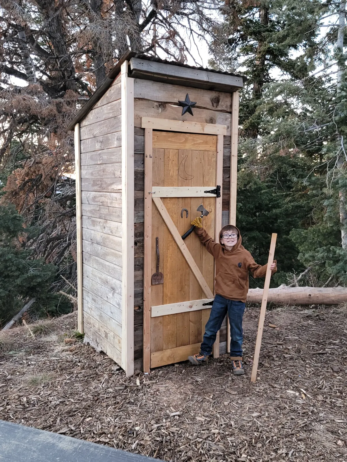 Completed mountain outhouse with barn door and metal star decoration