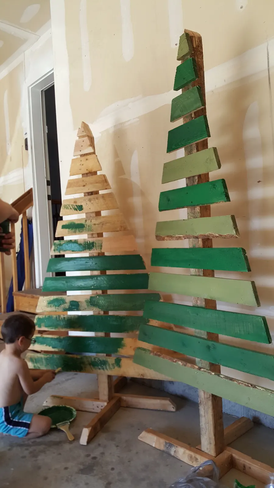 Green paint being applied to the assembled wooden trees.