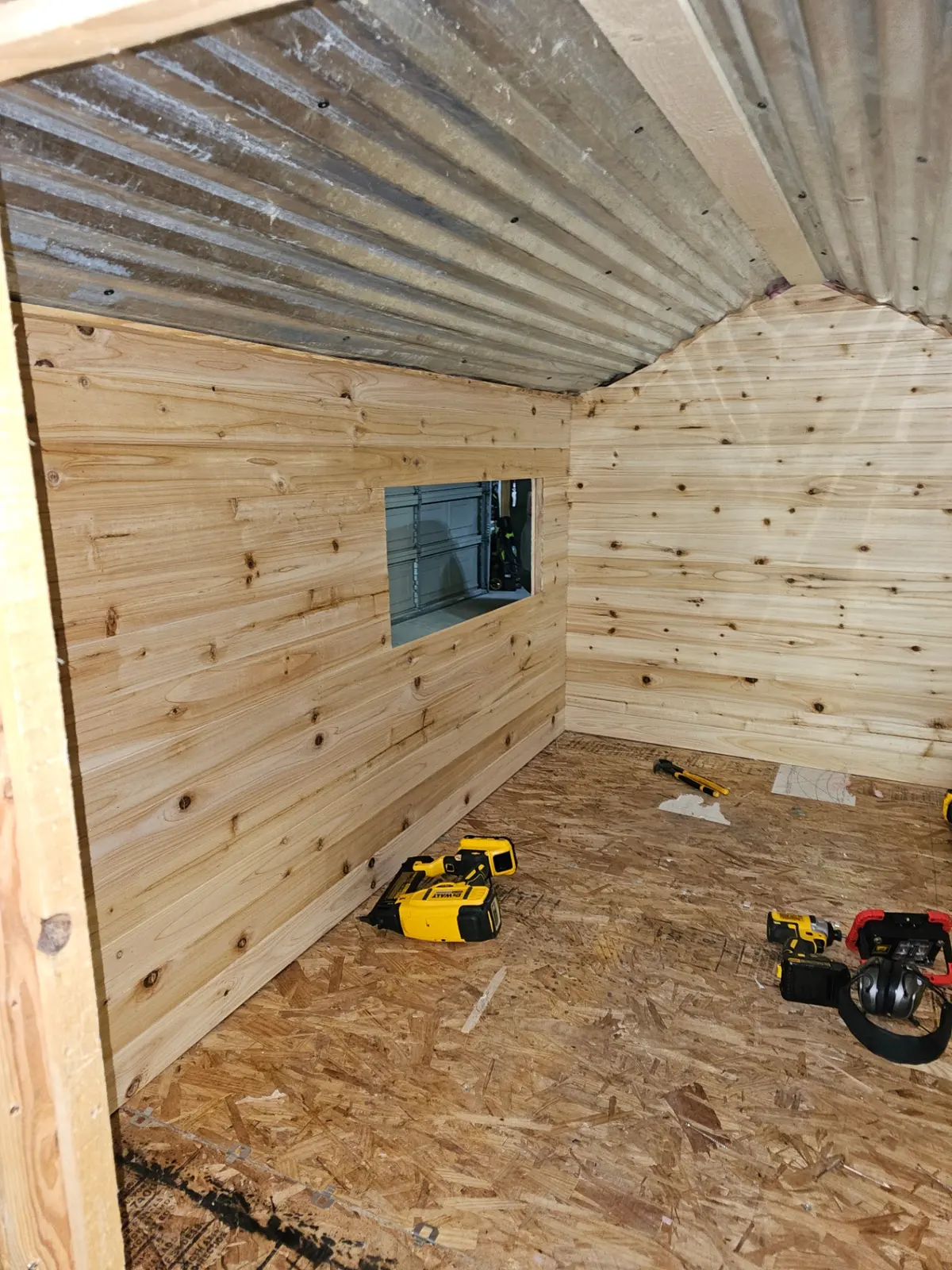 Interior with finished pine paneling and corrugated metal ceiling