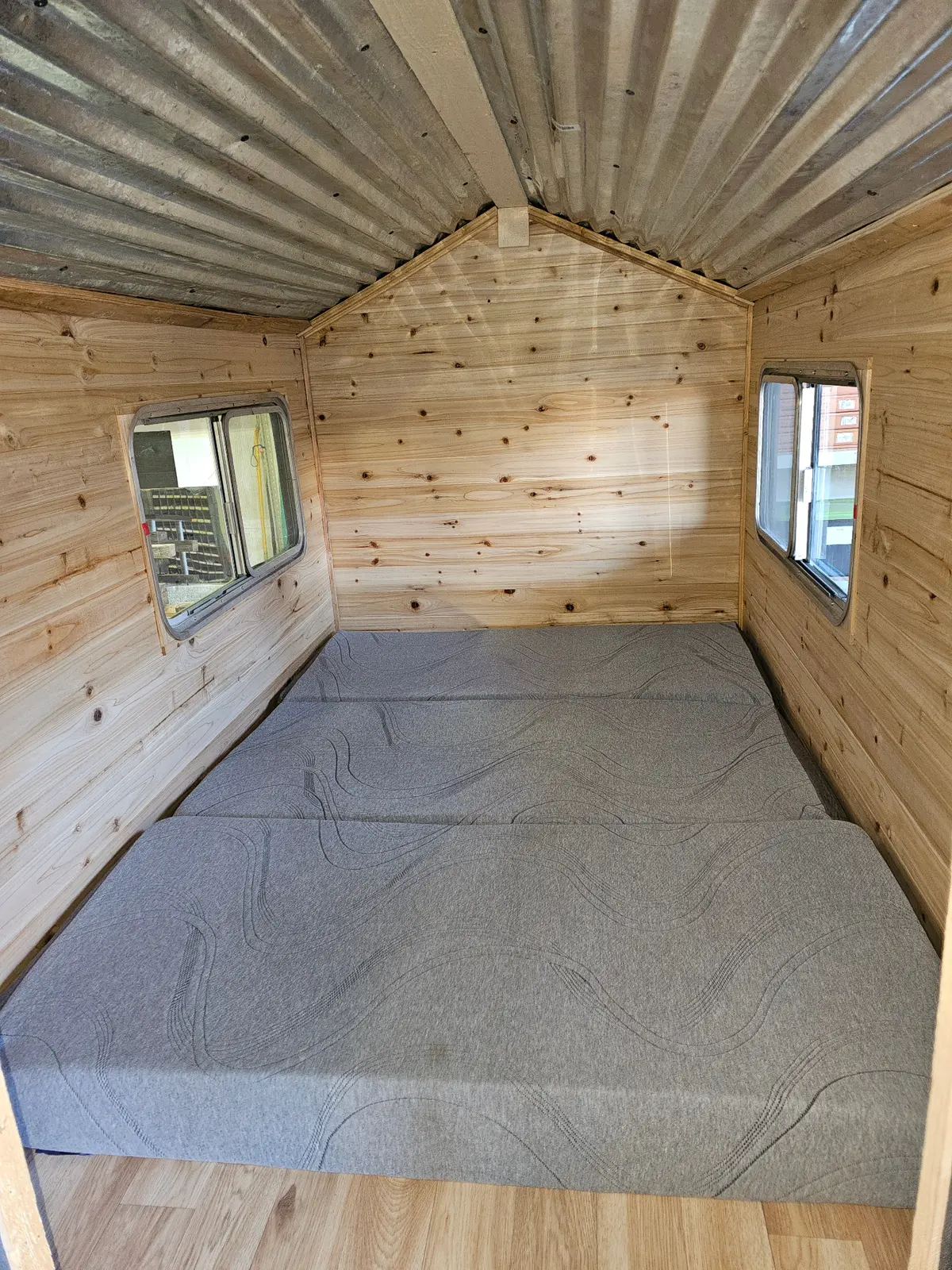 Cabin trailer interior with pine walls and comfortable sleeping area