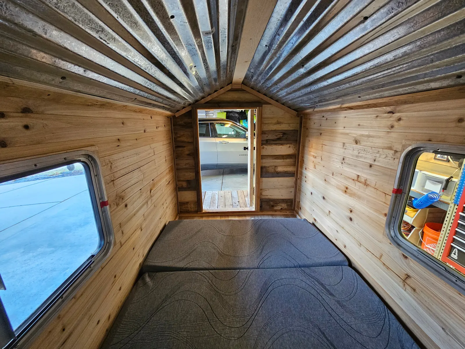 Cabin trailer interior view showing vaulted ceiling and windows