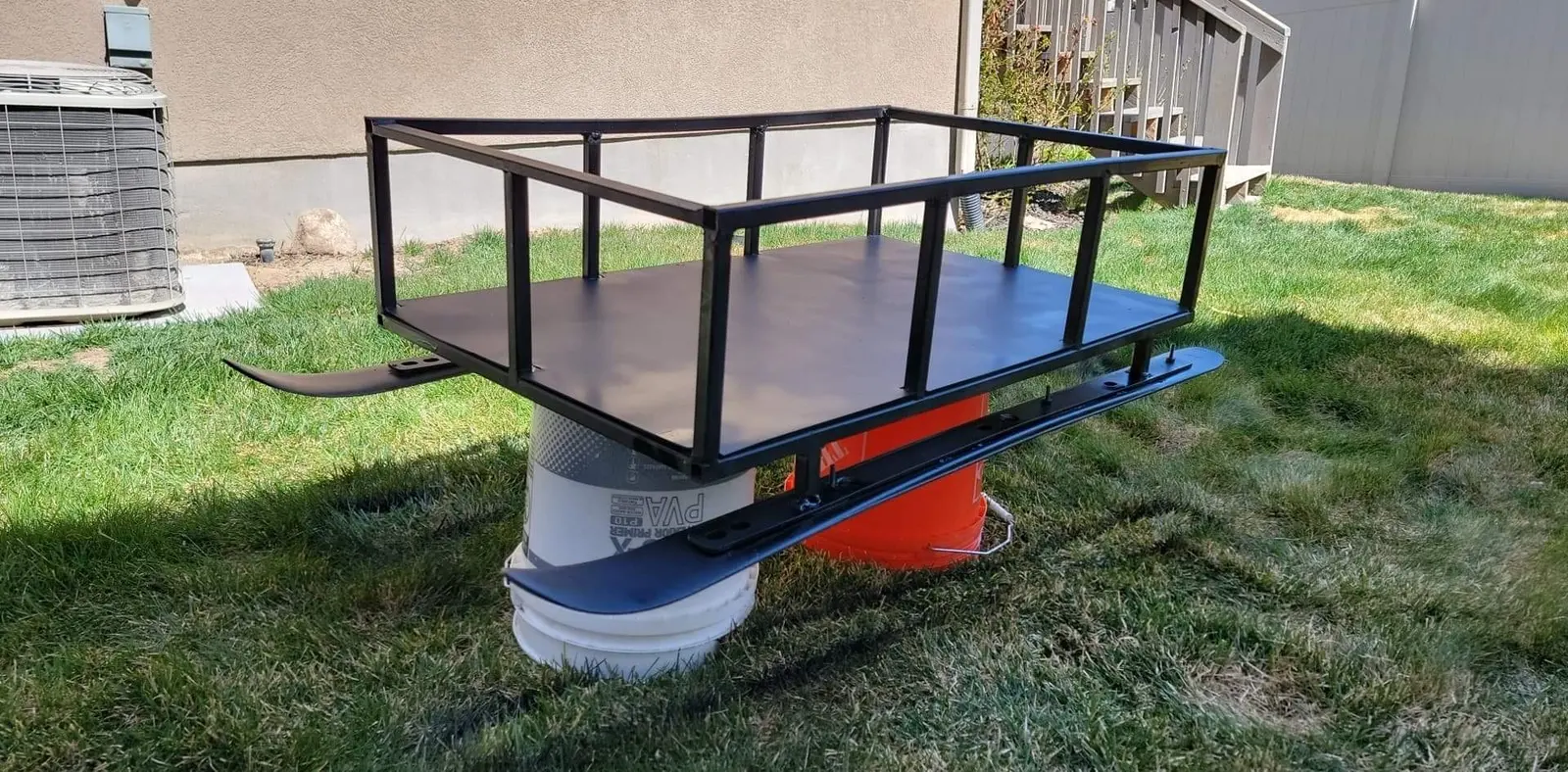Custom welded snowmobile sled with metal frame and repurposed skis in backyard