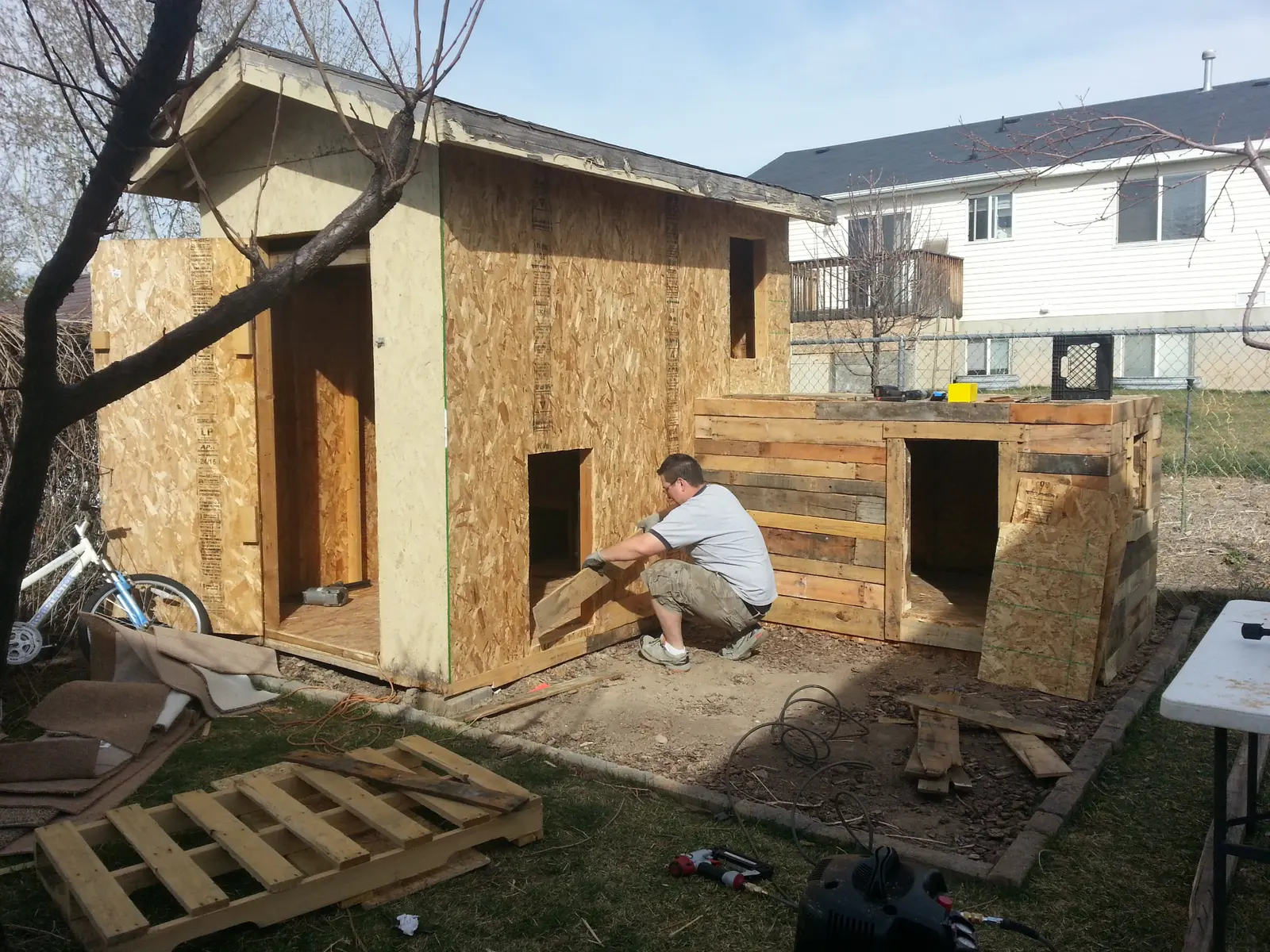 Western pallet playhouse construction - worker installing pallet walls