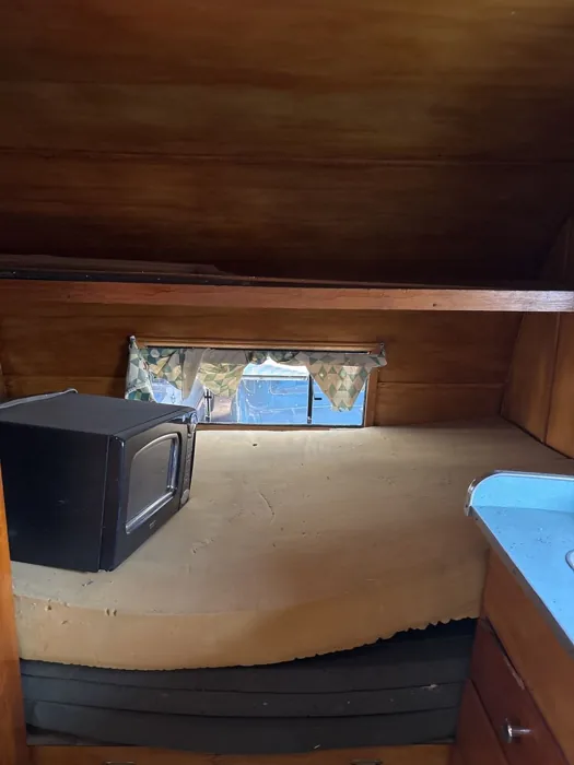 Original sleeping area with wood-paneled walls and the bed in place.