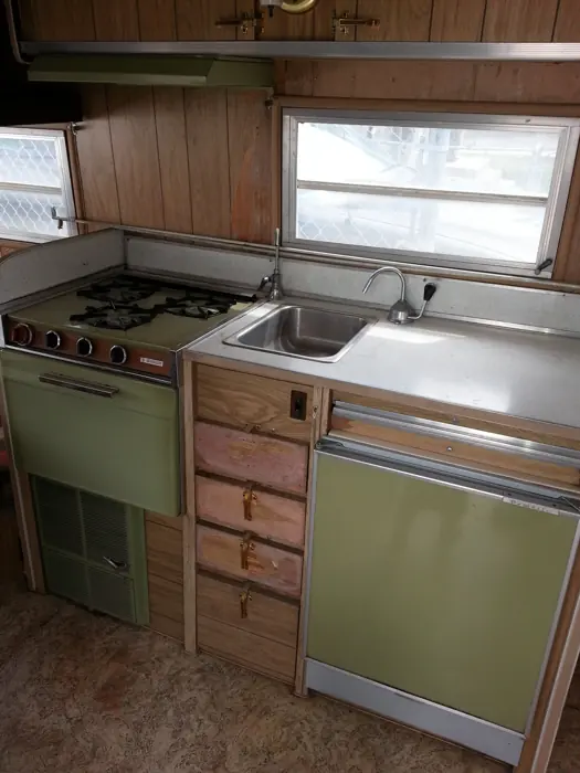 Original galley with green appliances and wood cabinets.
