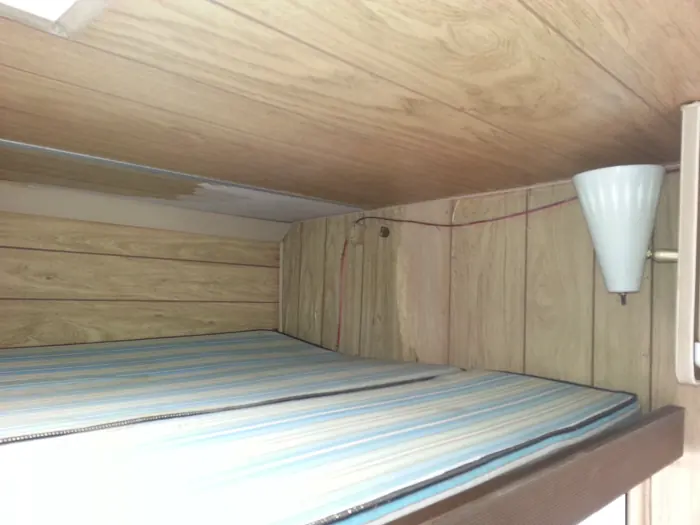 Original upper bunk and wood-paneled walls.