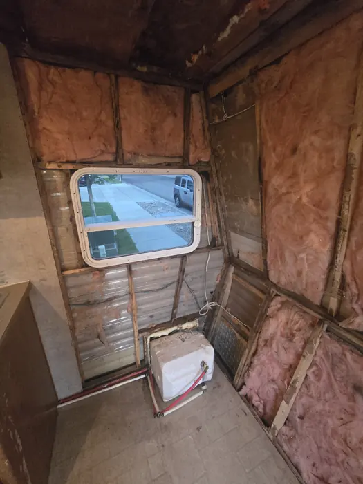 Exposed wall framing and insulation around the damaged window.