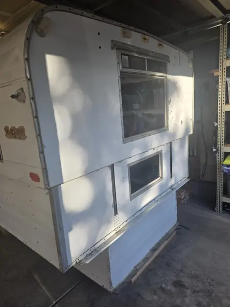 Three-quarter exterior view of the Alaskan camper before restoration