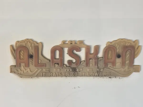 Original weathered Alaskan Camper emblem before the custom replacement