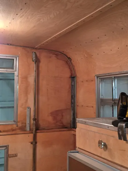 Unfinished camper wall and ceiling panels beside the entrance and cabinet during interior work