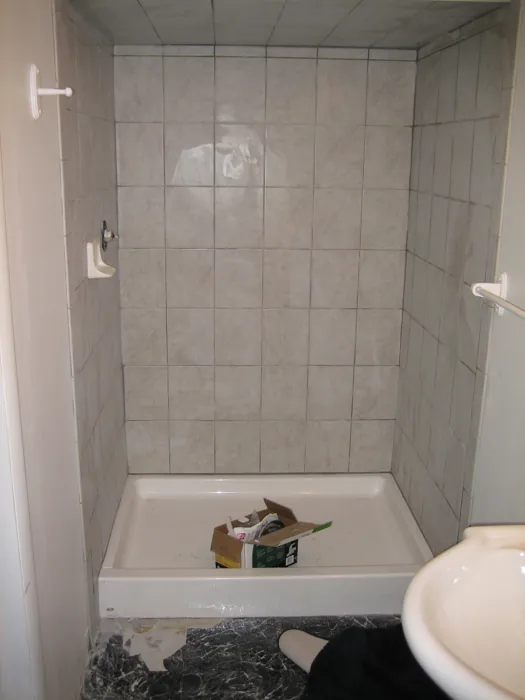 Finished tiled shower with the pedestal sink and toilet beside it.