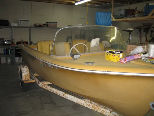 Yellow boat before restoration, viewed from the bow in the garage