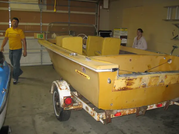 Yellow boat before restoration, showing the stern, hull and trailer