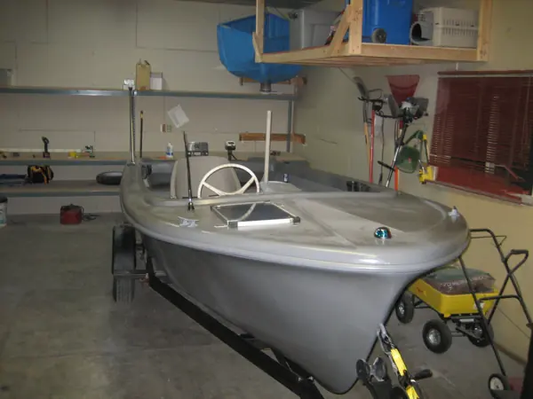 Restored gray boat in a front three-quarter view with hull, windshield and trailer