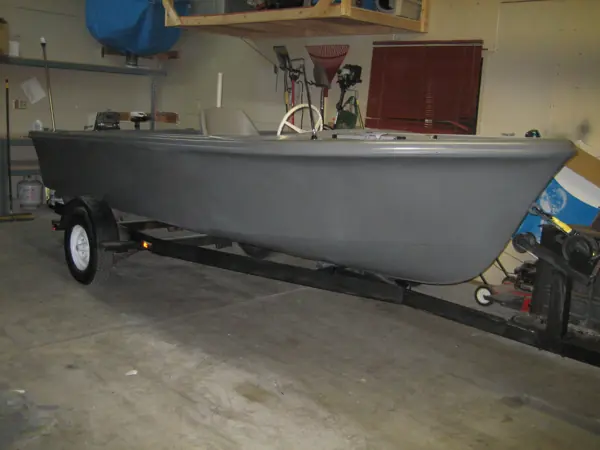 Restored gray boat in a broadside view showing the full hull and trailer