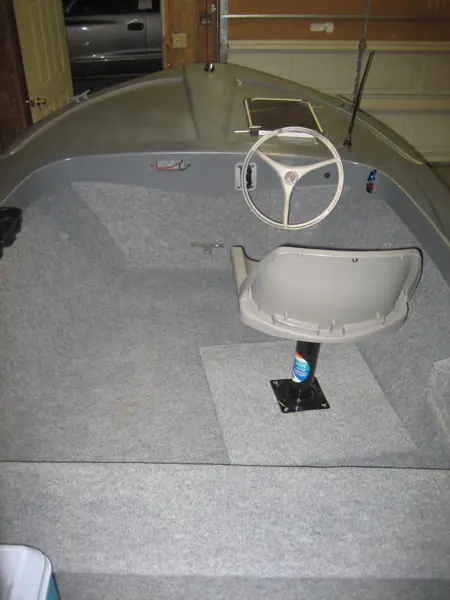 Finished boat cockpit with pedestal seat, steering wheel and gray carpeted deck