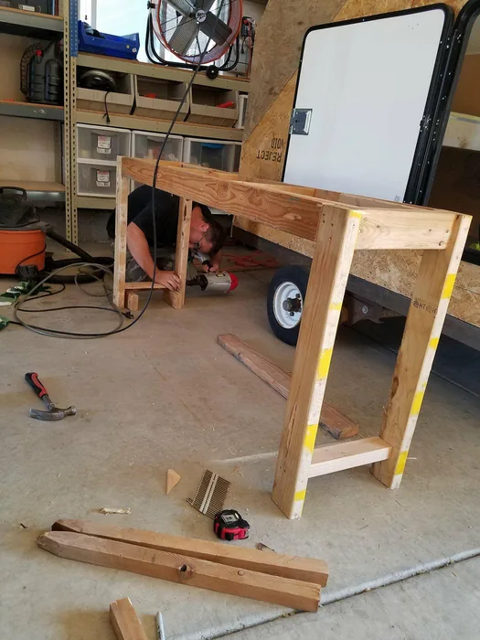 Wooden console-table frame standing in the workshop during construction.