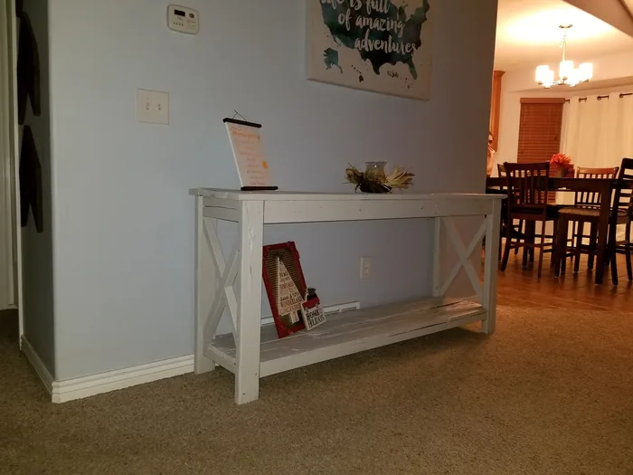 Completed white console table with a natural wood top and lower shelf.