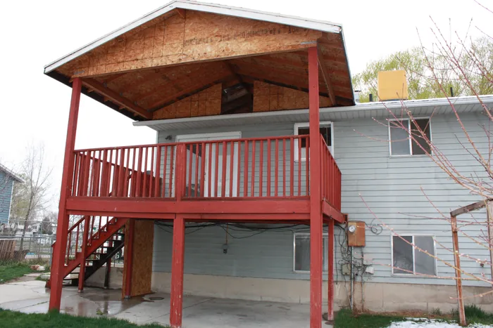 Earlier view of the covered deck with red railings and stairs.