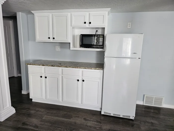 Completed white cabinet installation with a countertop, microwave and refrigerator.