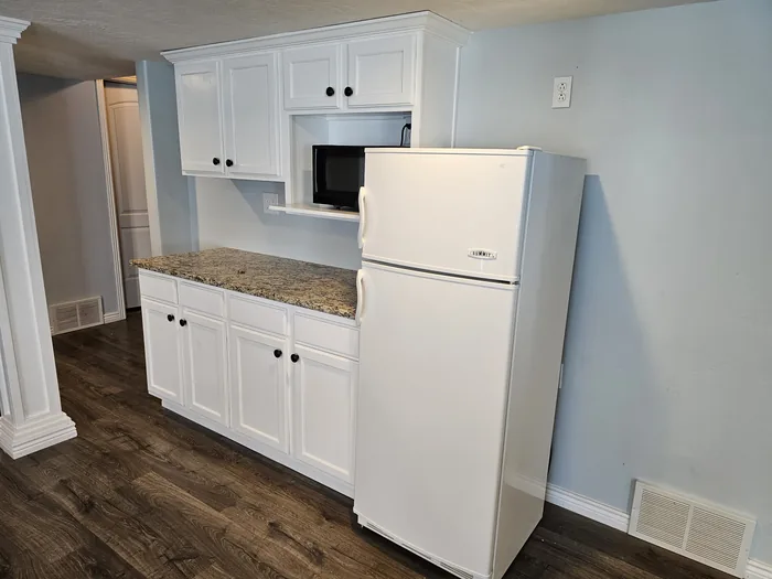 Angled view of the finished cabinetry, countertop and refrigerator.