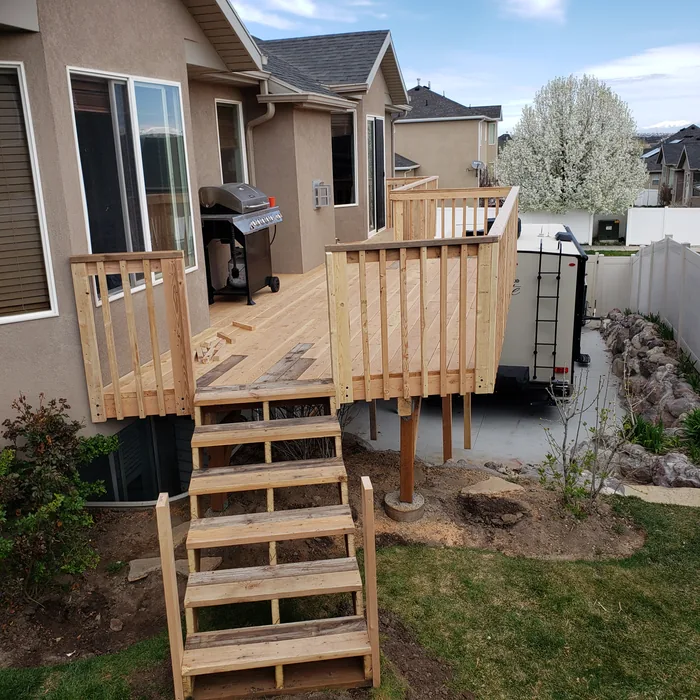 Completed raised wooden deck with broad stairs and full railings.