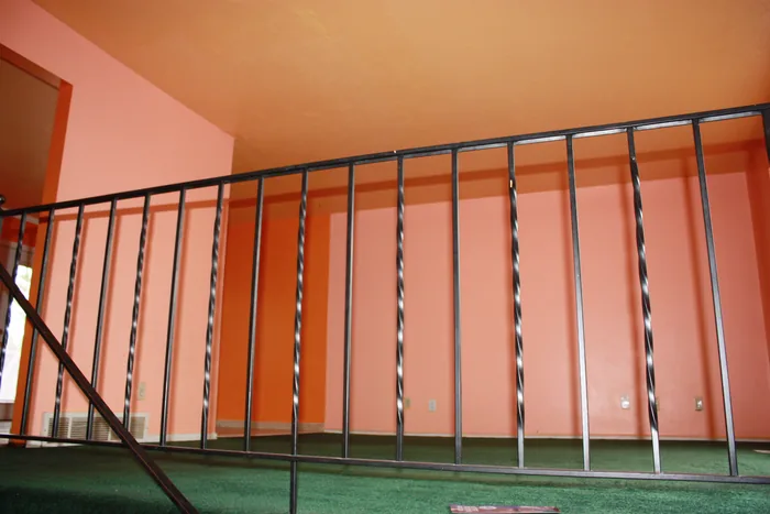 Living room before renovation, showing orange walls, green carpet and the stair railing.