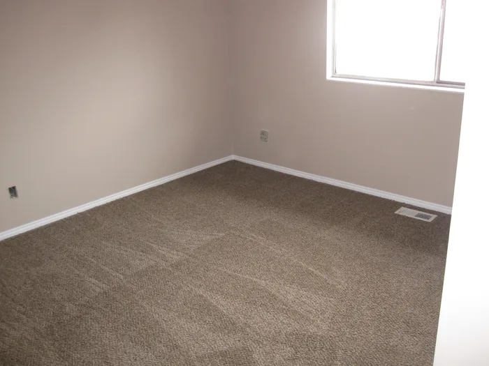 Finished bedroom with neutral walls, white trim and fresh carpet.