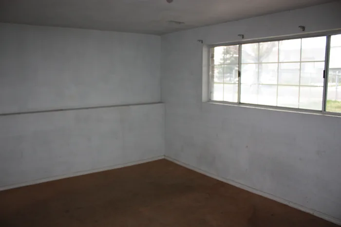 Basement living room before renovation, with unfinished-looking walls and older flooring.