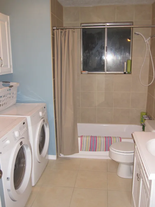 Finished bathroom and laundry area with white cabinetry and updated finishes.