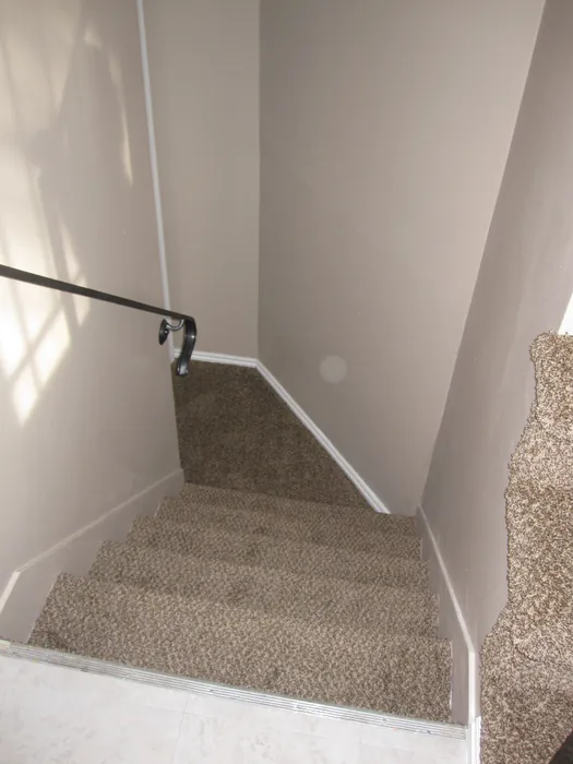 Finished stairway with neutral walls, white trim and updated carpet.