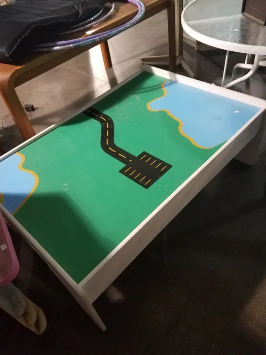 Original play table with painted roads and blue-and-green scenery before the storage-bin opening
