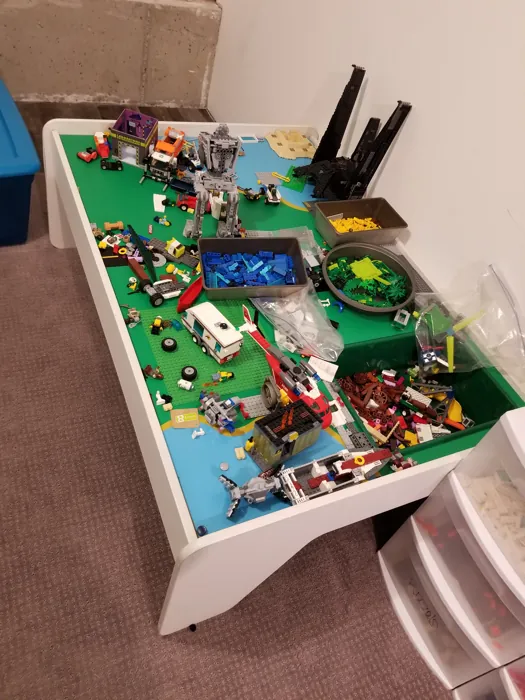 Finished play table filled with Lego buildings, vehicles and sorted bricks