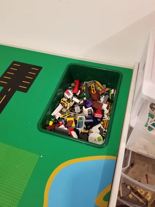 Green removable storage bin holding Lego pieces within the table surface
