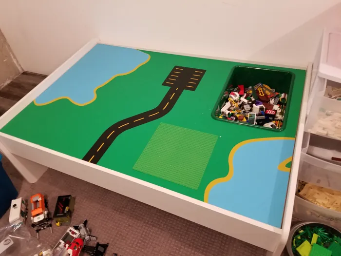 Lego play table with a recessed green brick bin, building baseplate and painted roads
