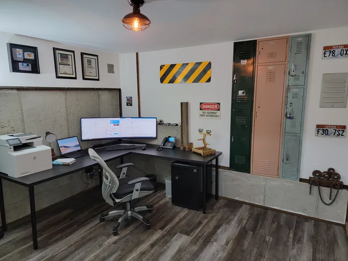 Home office with a corner desk, wood-look floor and industrial-style wall accents.