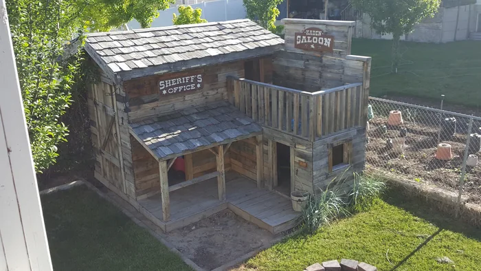 Later view of the completed western playhouse, with its porch, balcony and wooden roof.