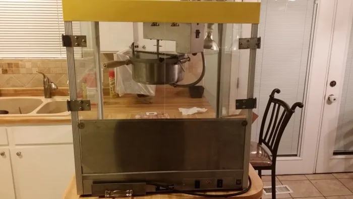 Front view of the cleaned popcorn machine with kettle suspended above the lower cabinet