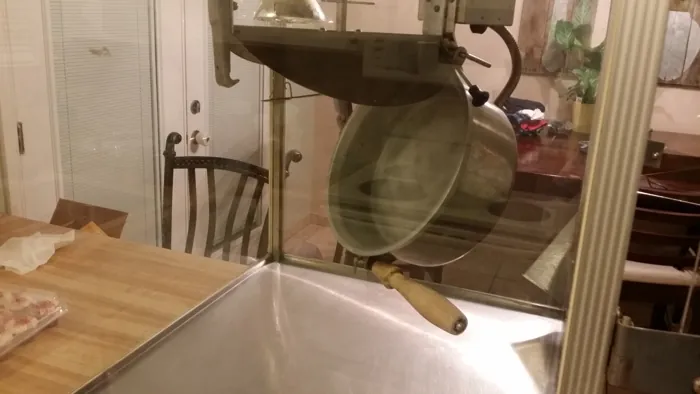 Popcorn kettle tilted open inside the cleaned glass cabinet