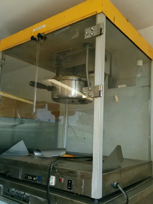 Original popcorn machine with worn yellow canopy, marked glass and a weathered metal cabinet