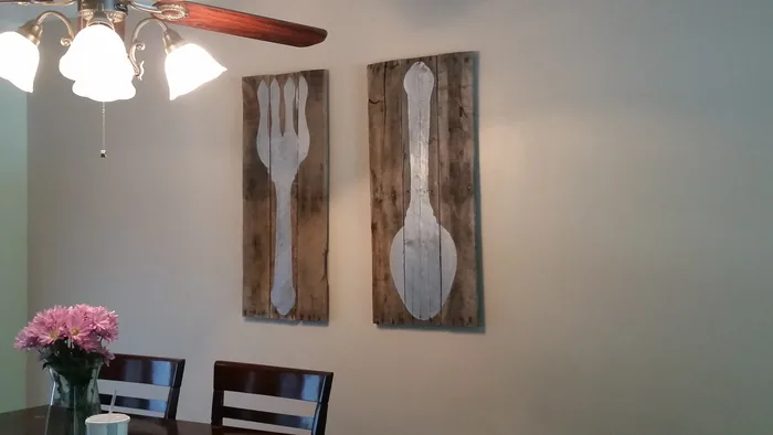 Fork and spoon wall panels displayed above a dining table.