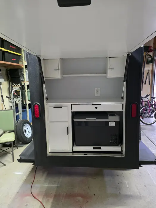 Open rear hatch revealing the galley counter, cabinets and refrigerator.